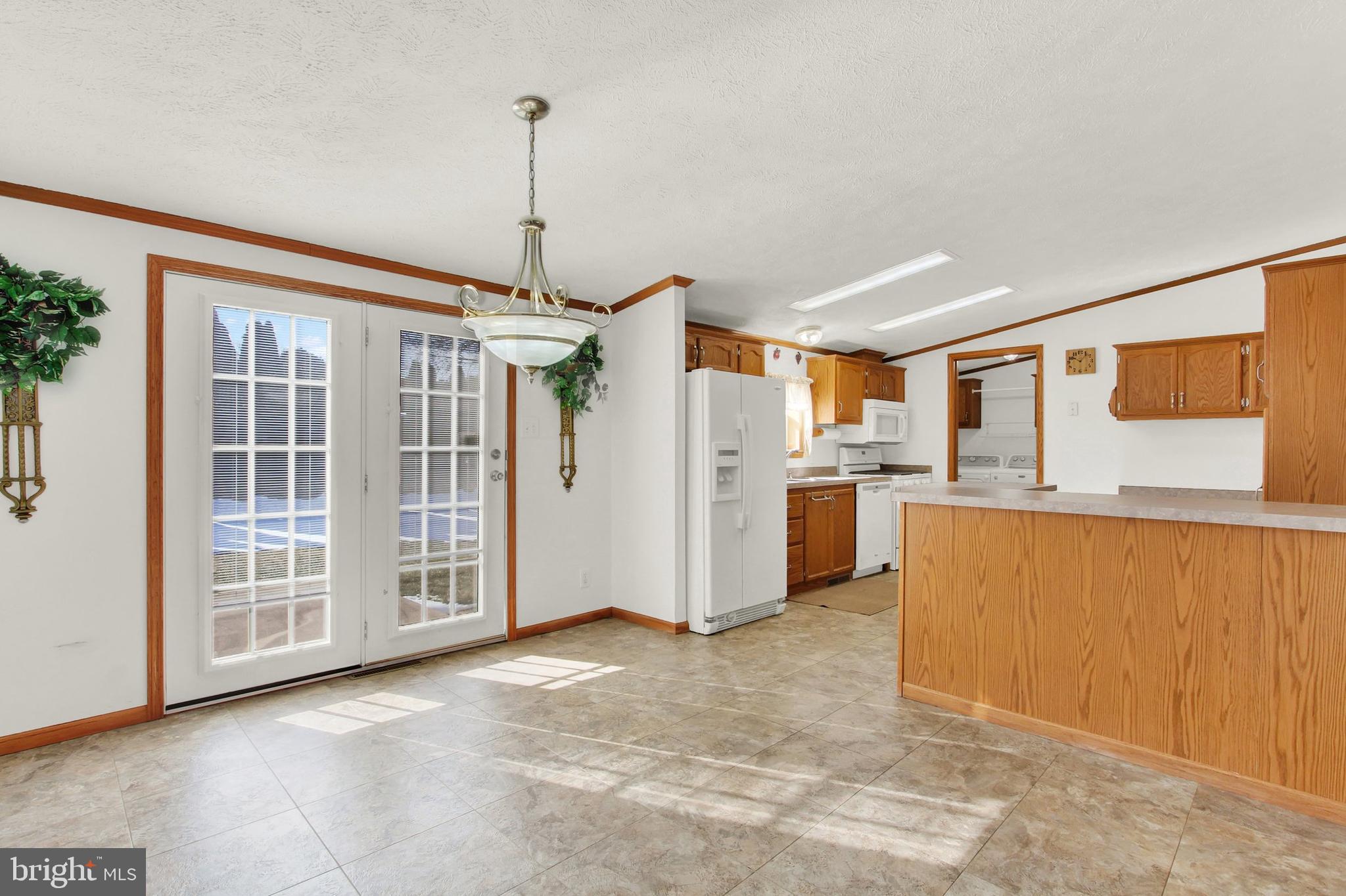 Kitchen with wood cabinets, a breakfast peninsula, tiled floor, and sunlit French doors.