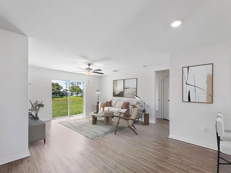Living room with a light sofa, abstract artwork, and sliding glass doors opening to a lawn.