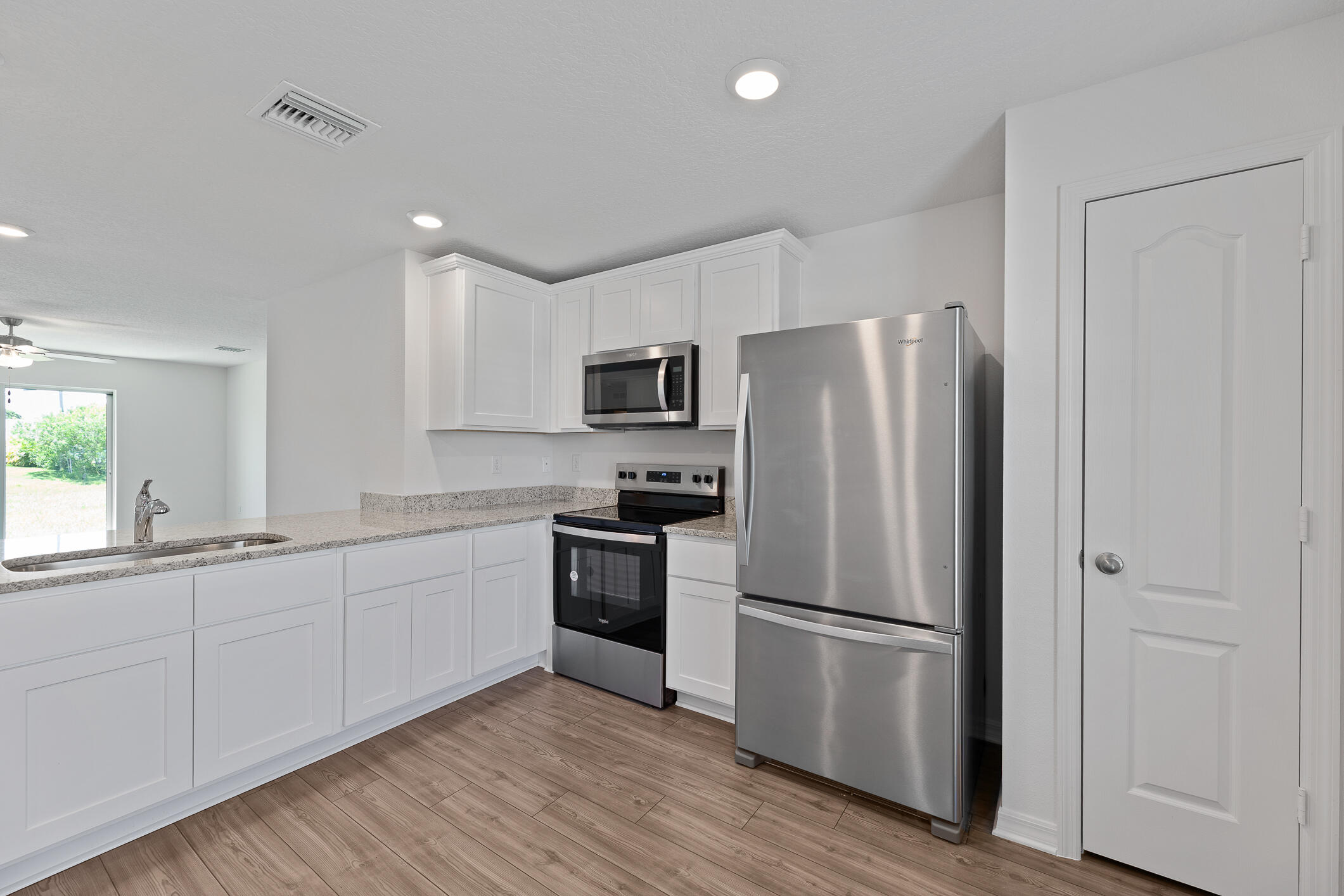 Kitchen with white cabinets, granite counters, and stainless steel appliances.