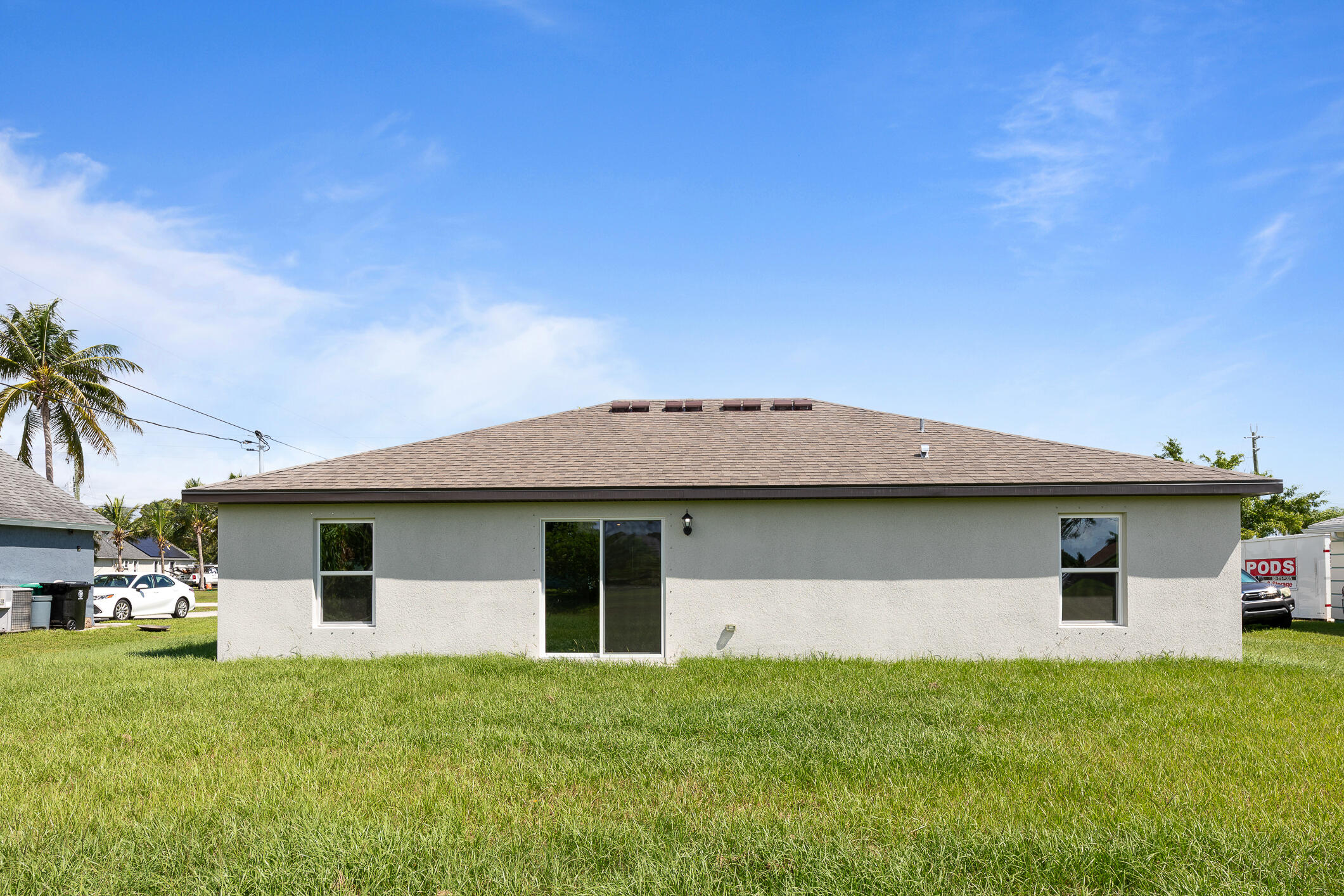 Rear exterior of a single-story home with a wide shingled roof and sliding glass door.
