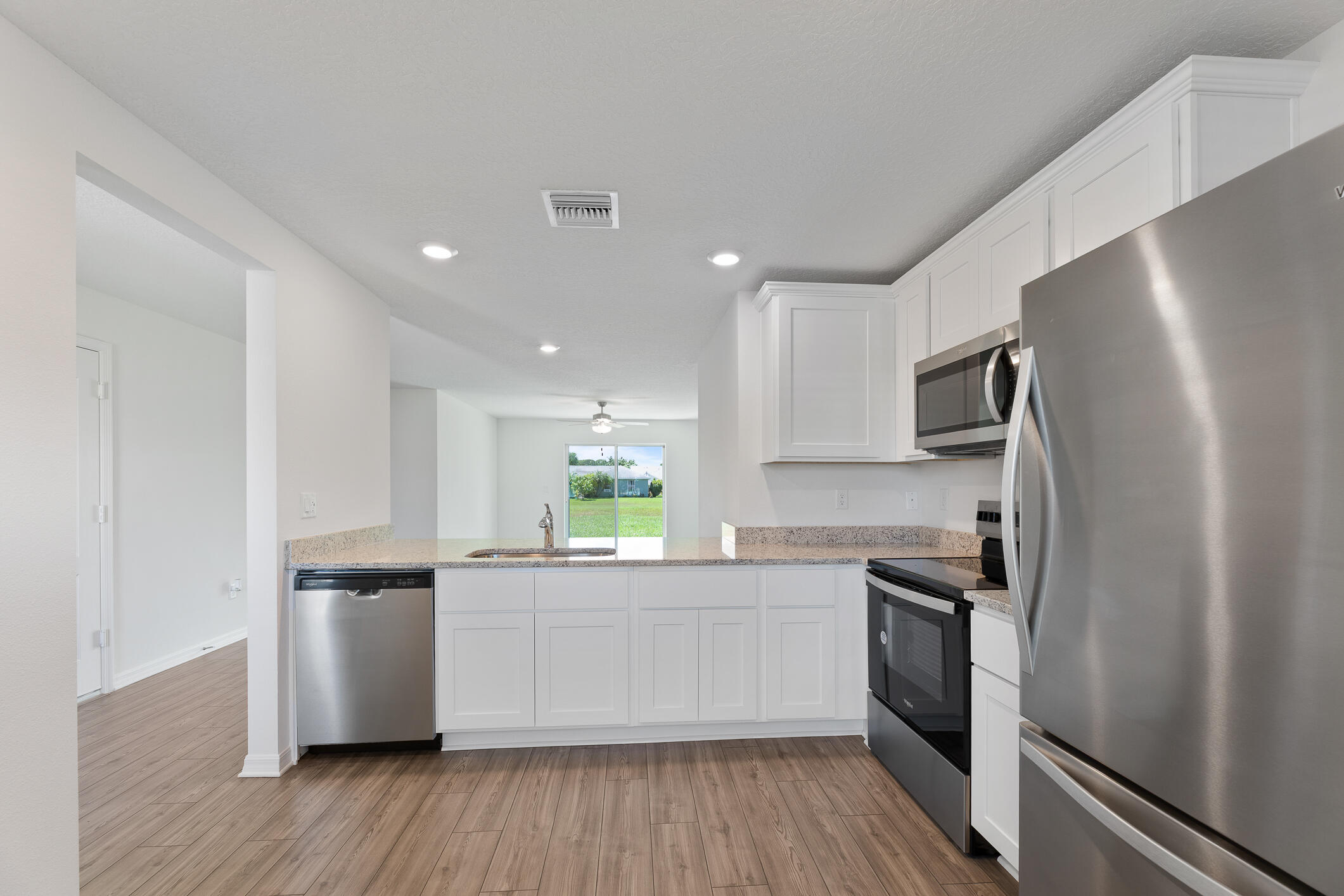Bright kitchen with white cabinets, stainless steel appliances, and a breakfast bar overlooking the living area.