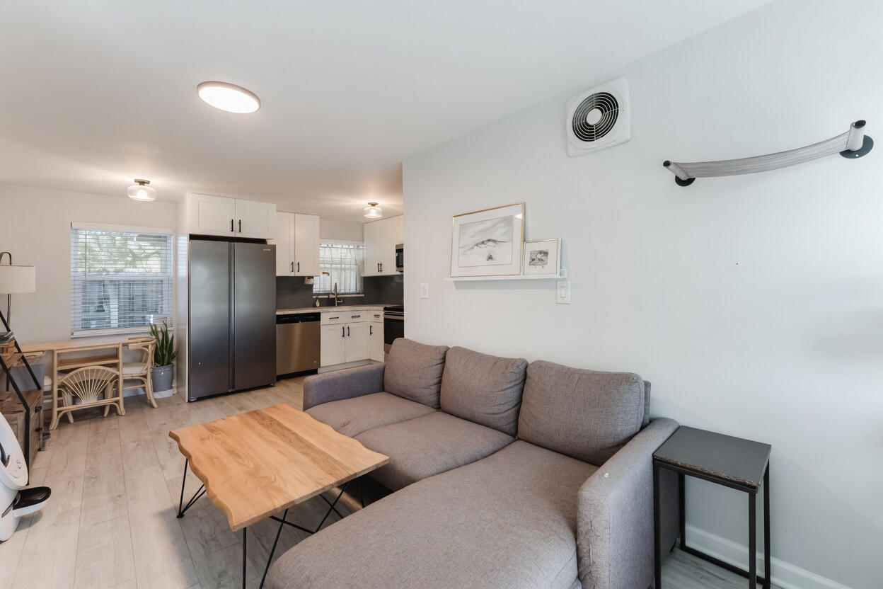 Living room with a gray sectional and wooden coffee table beside an open kitchen.