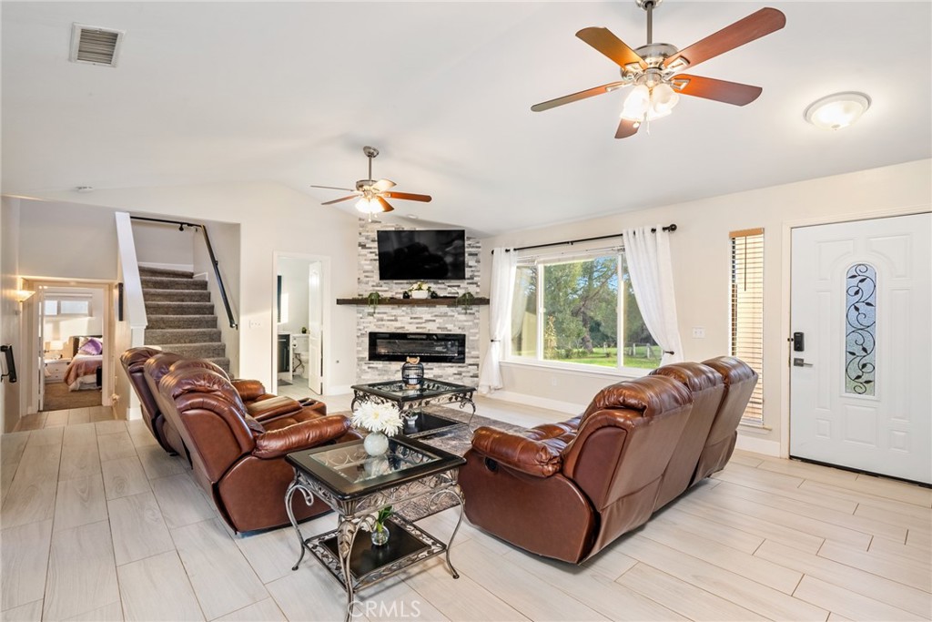 Living room with brown leather recliners, a stone fireplace, and a large window overlooking greenery.