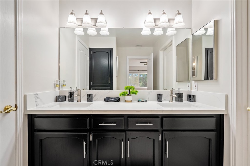 Bathroom with a black double vanity, white marble-look counter, and large mirror.