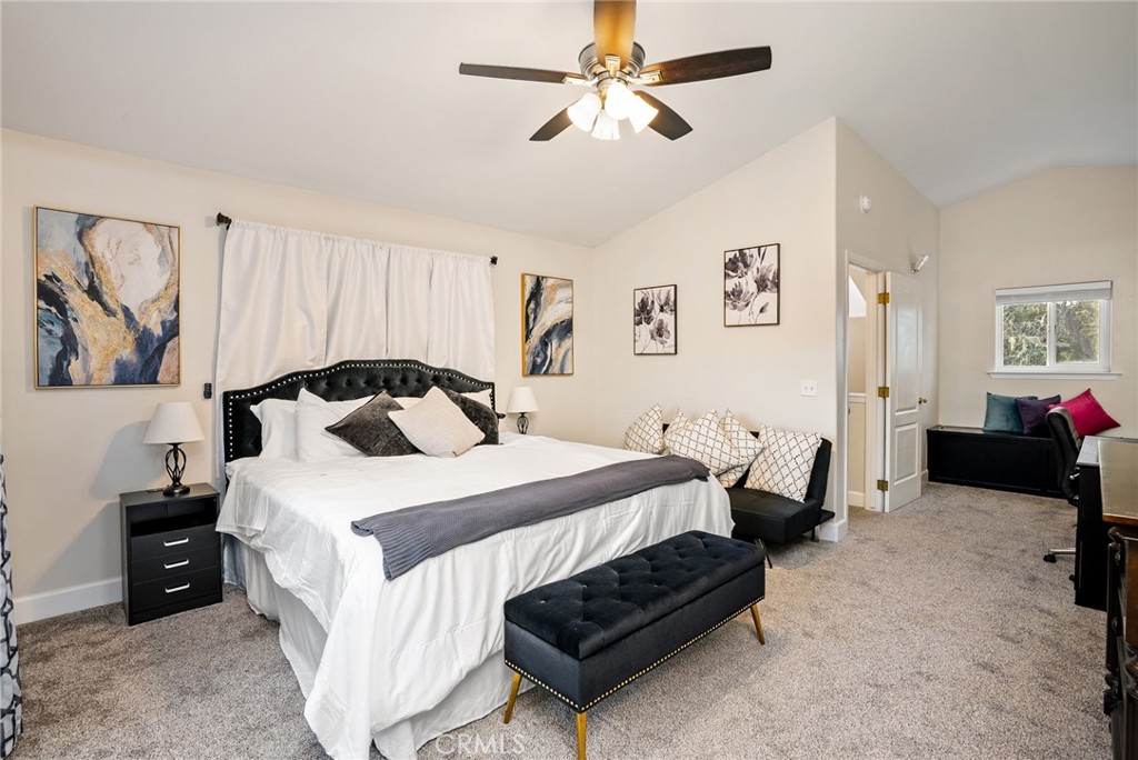 Staged bedroom with a white bed, black upholstered headboard, and seating area by the window.