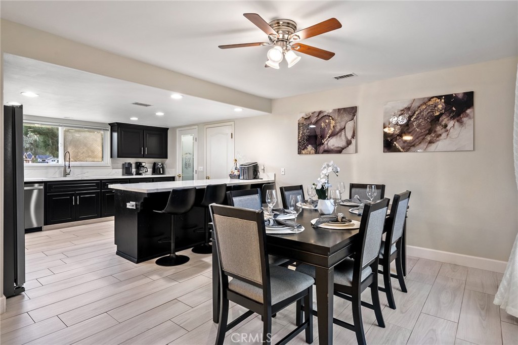 Open-plan kitchen and dining area with black cabinets, island seating, and a set dining table.
