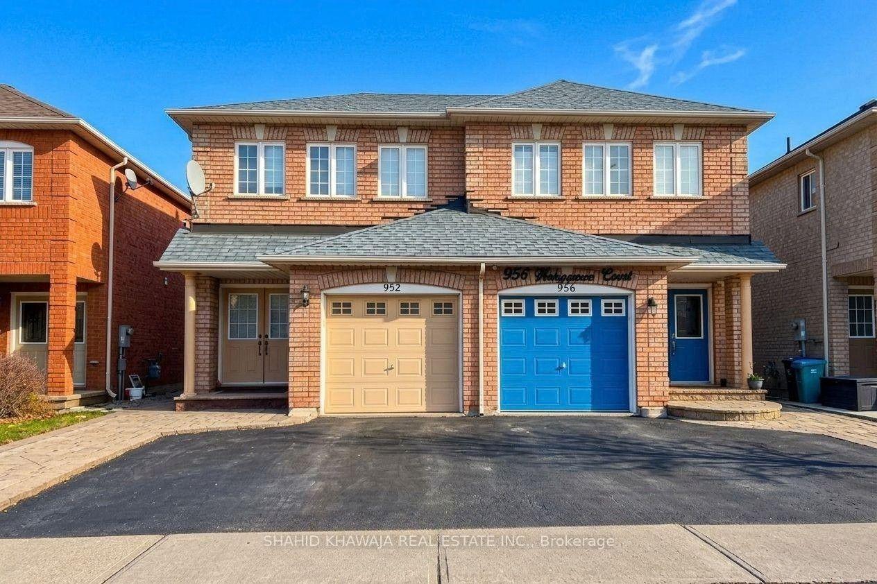 Two-storey brick home with a beige garage door beside an attached home with a blue garage door.