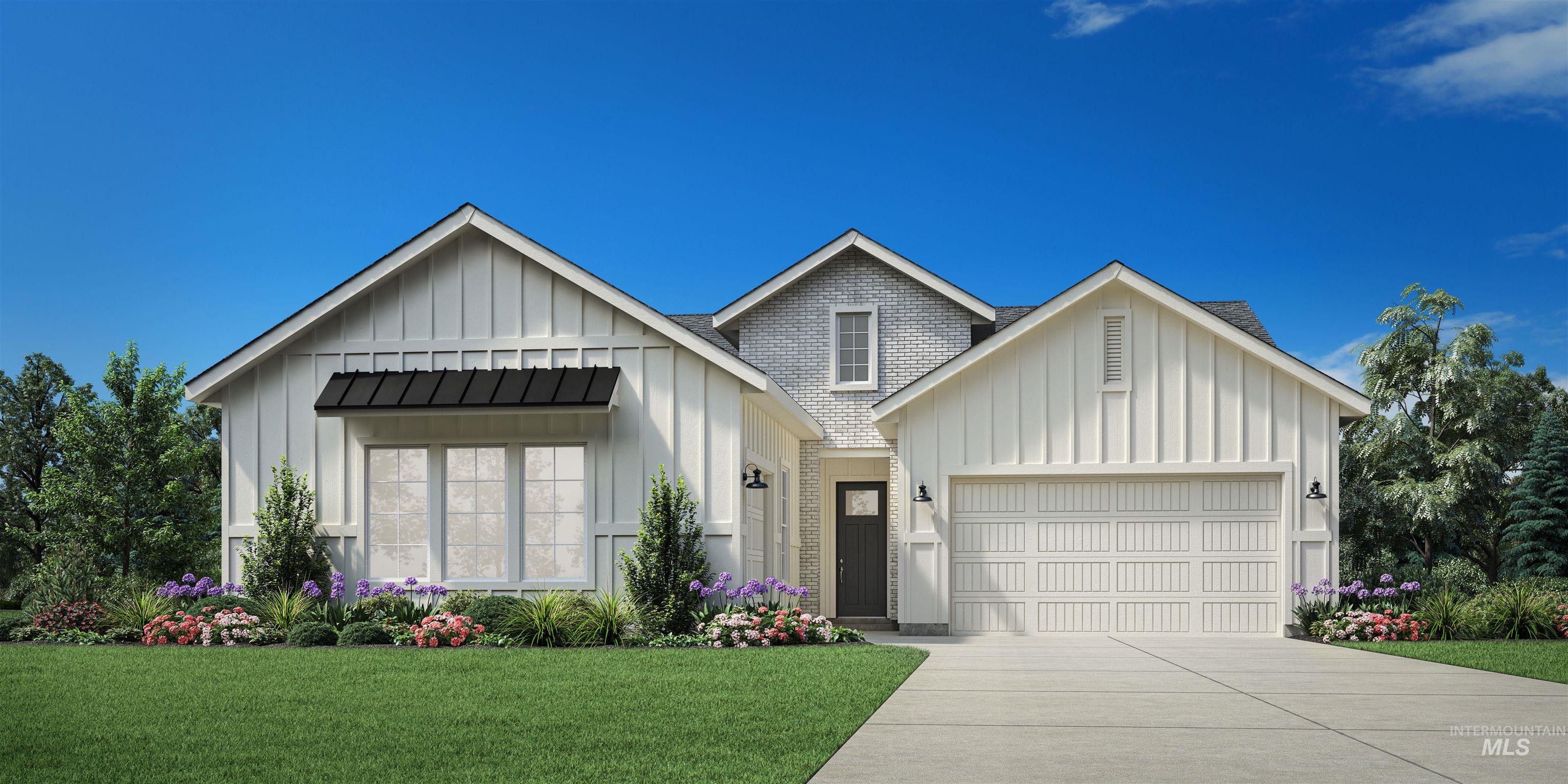 White gabled house with a brick center section, landscaped flower beds, and a two-car garage.