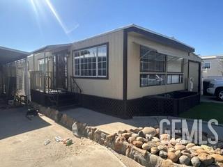 Single-story modular home with large windows, black skirting, and a rock-lined walkway.