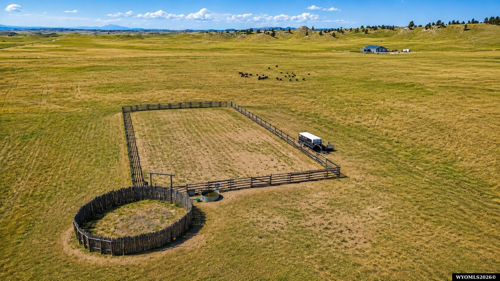 Rural pasture with fenced paddocks, cattle, and a distant barn, viewed from above.