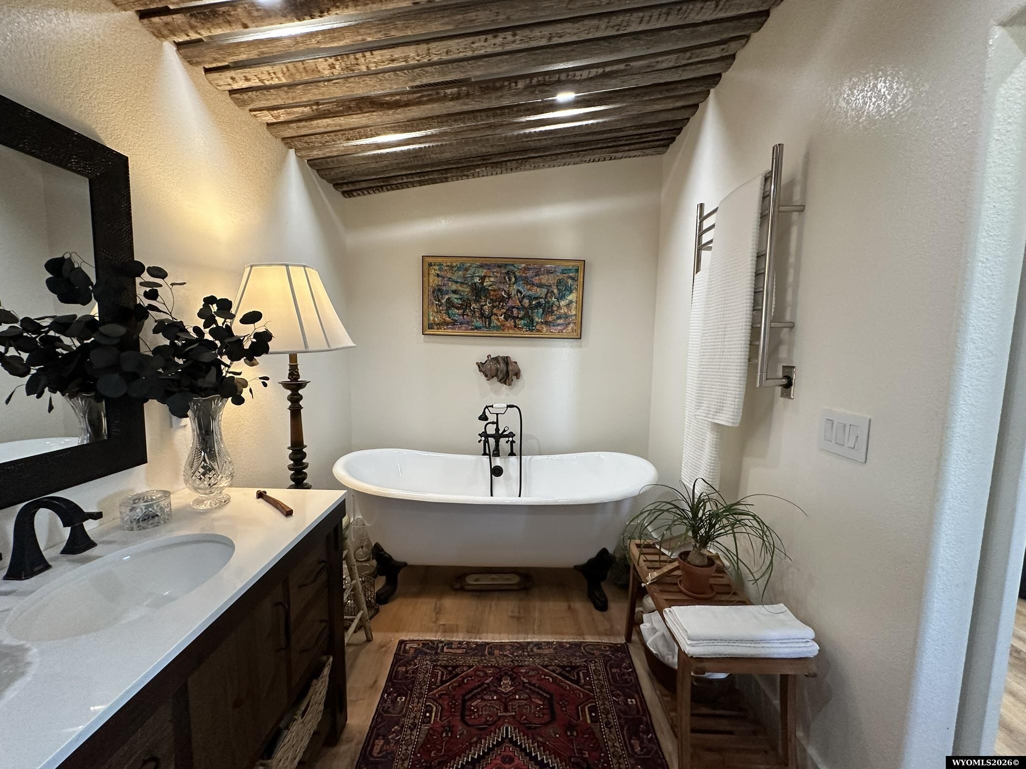 Bathroom with a freestanding tub, exposed wood ceiling beams, and dark wood vanity.
