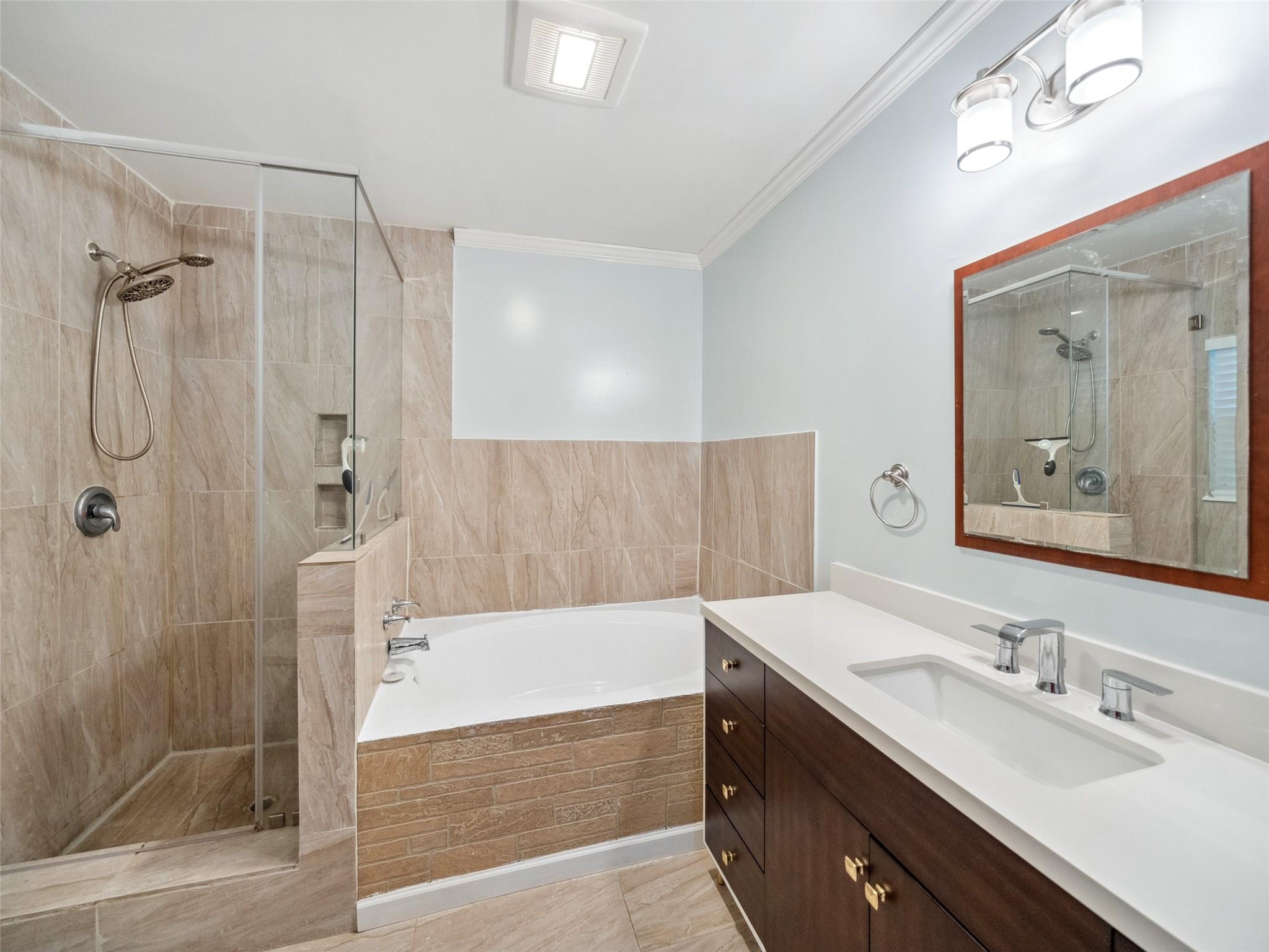 Bathroom with a tiled glass shower, built-in tub, and dark wood vanity.