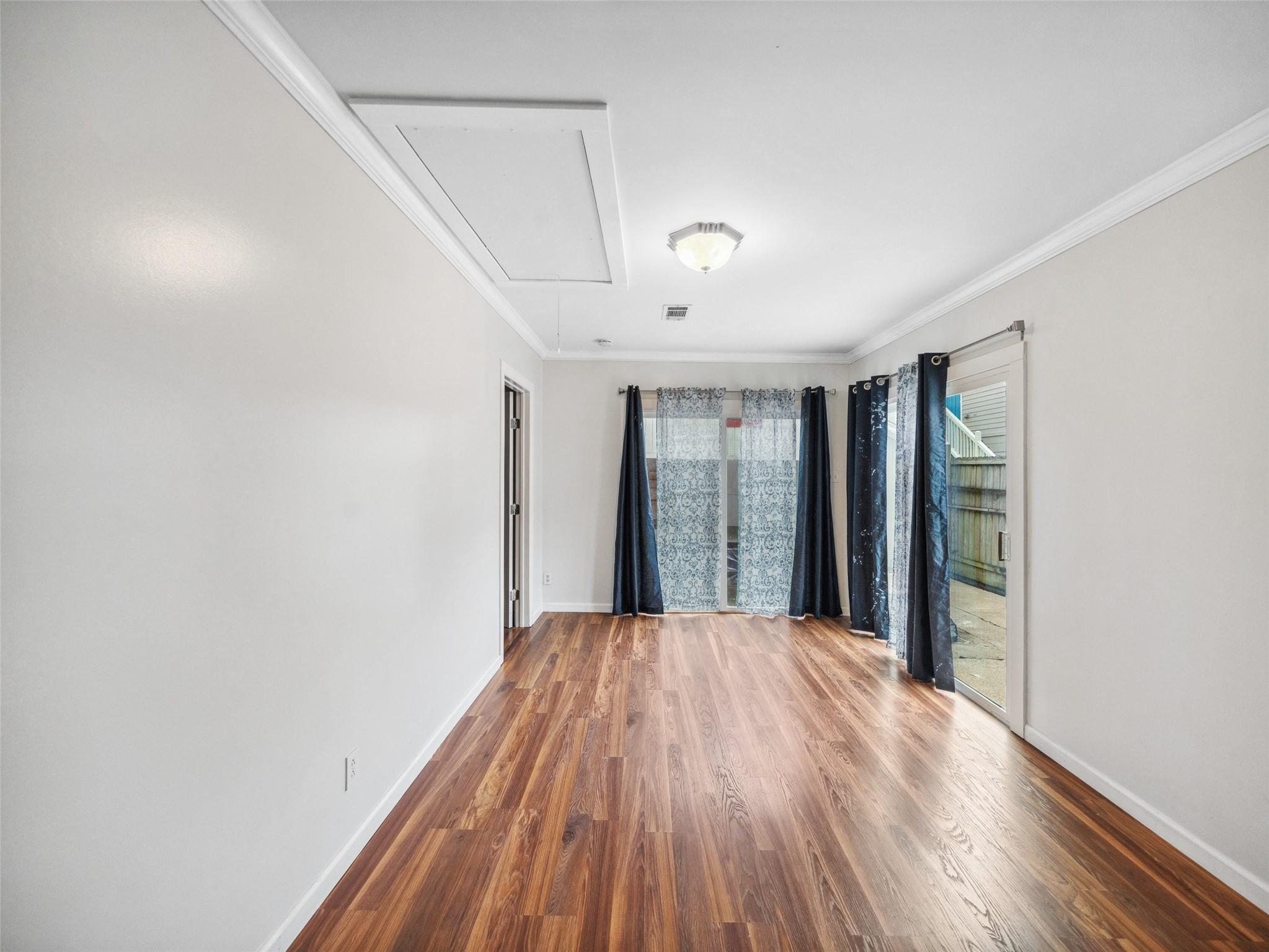 Empty room with wood floors, blue curtains, and a sliding glass door to a fenced patio.