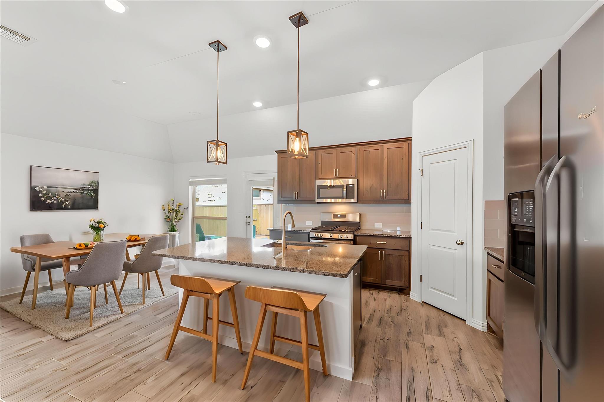 Open-plan kitchen and dining area with a large island, warm wood cabinets, and pendant lights.