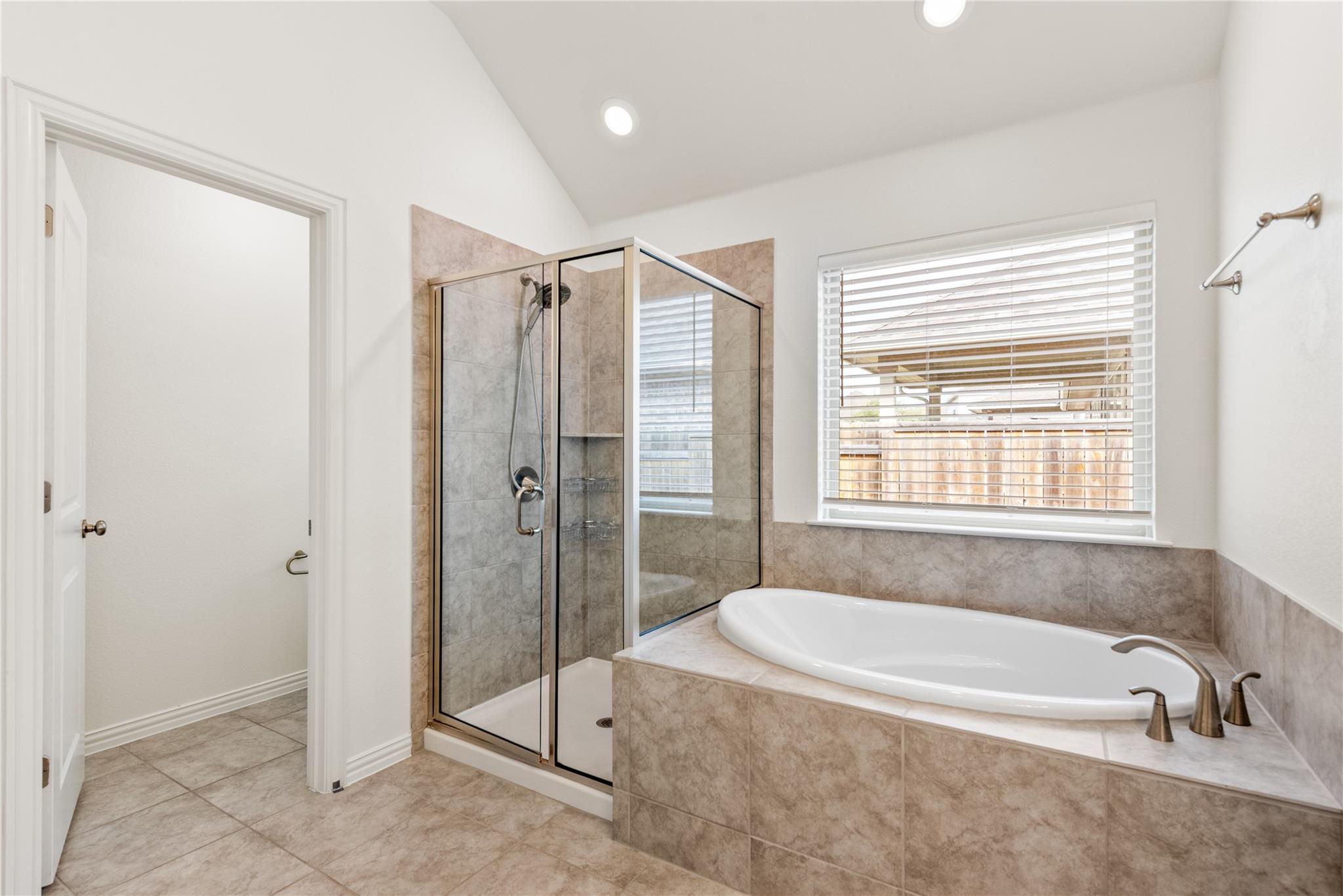 Bathroom with a glass shower, beige tile, and a large built-in soaking tub.