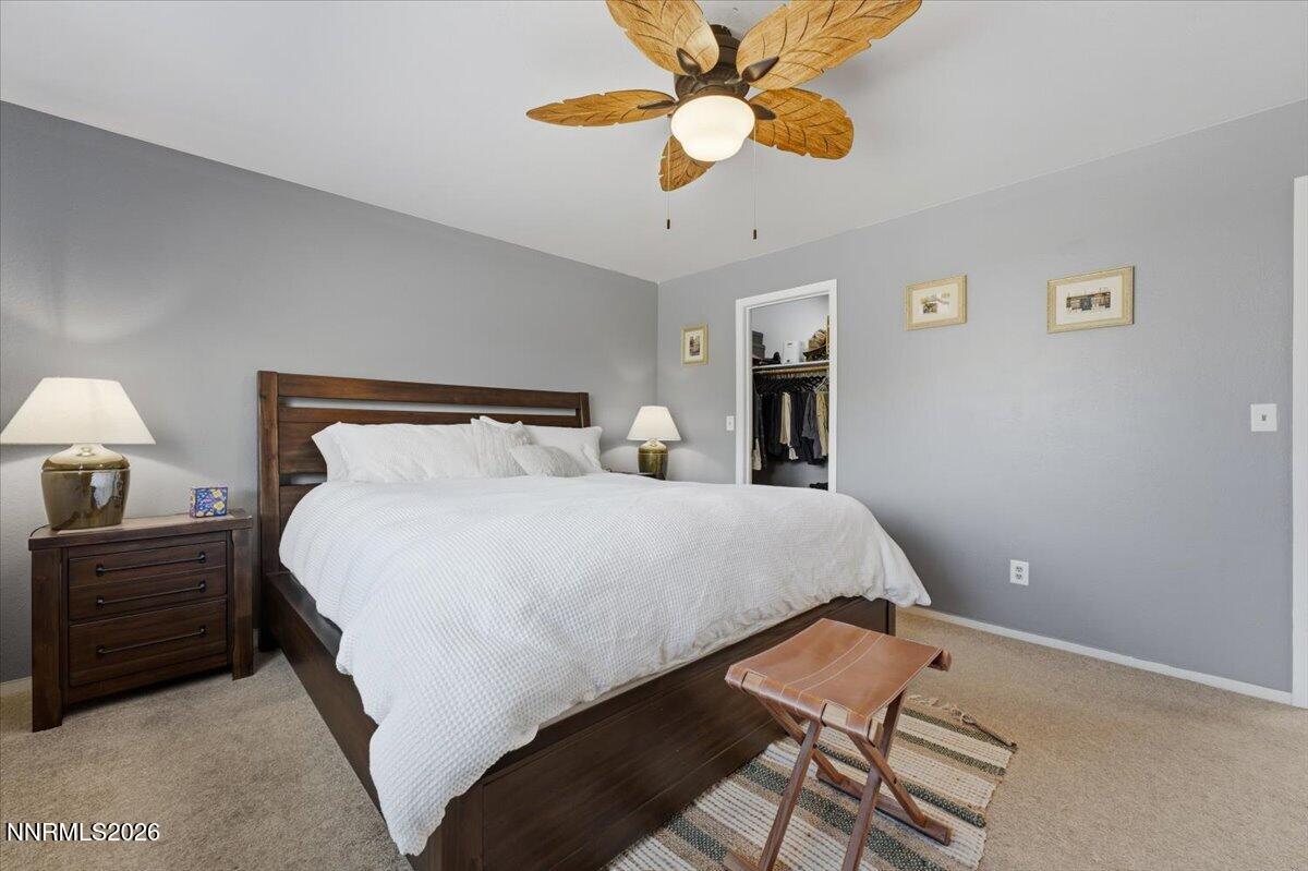 Furnished bedroom with a dark wood bed, white bedding, and a ceiling fan with wood-blade shades.