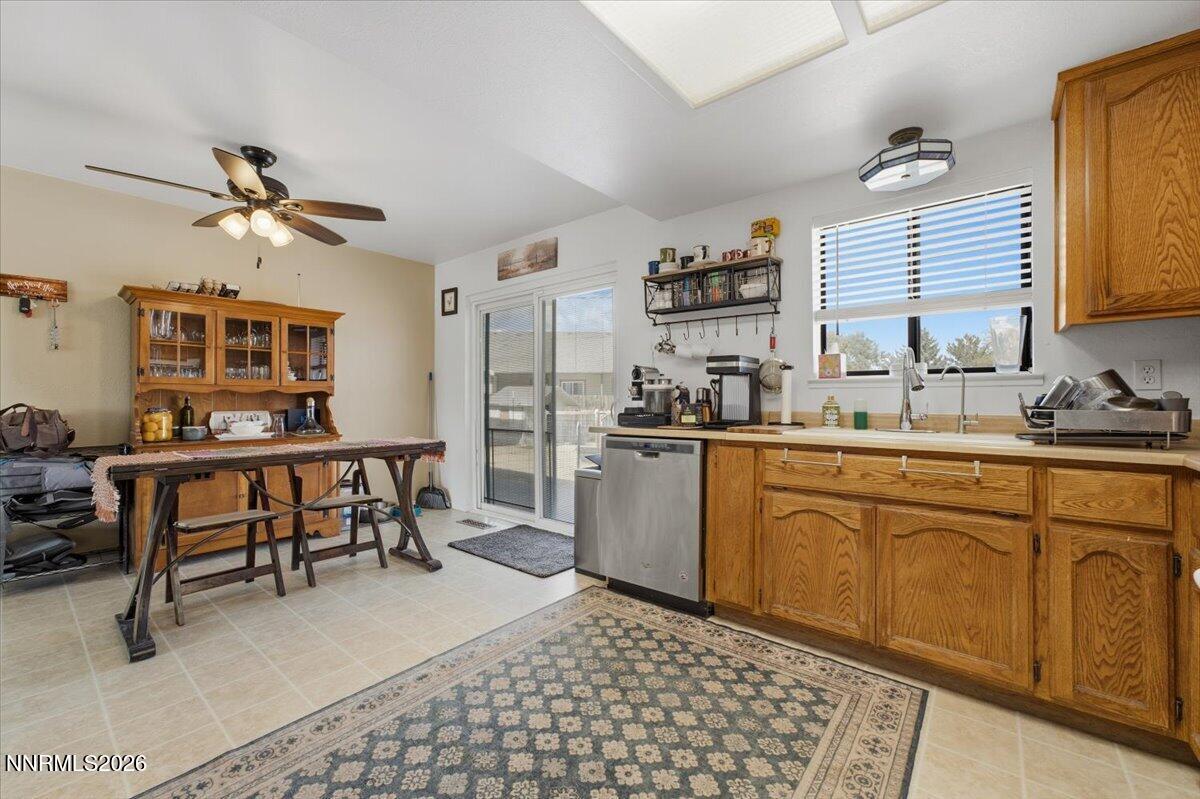 Kitchen with wood cabinets, stainless-steel dishwasher, and dining table beside a sliding glass door.