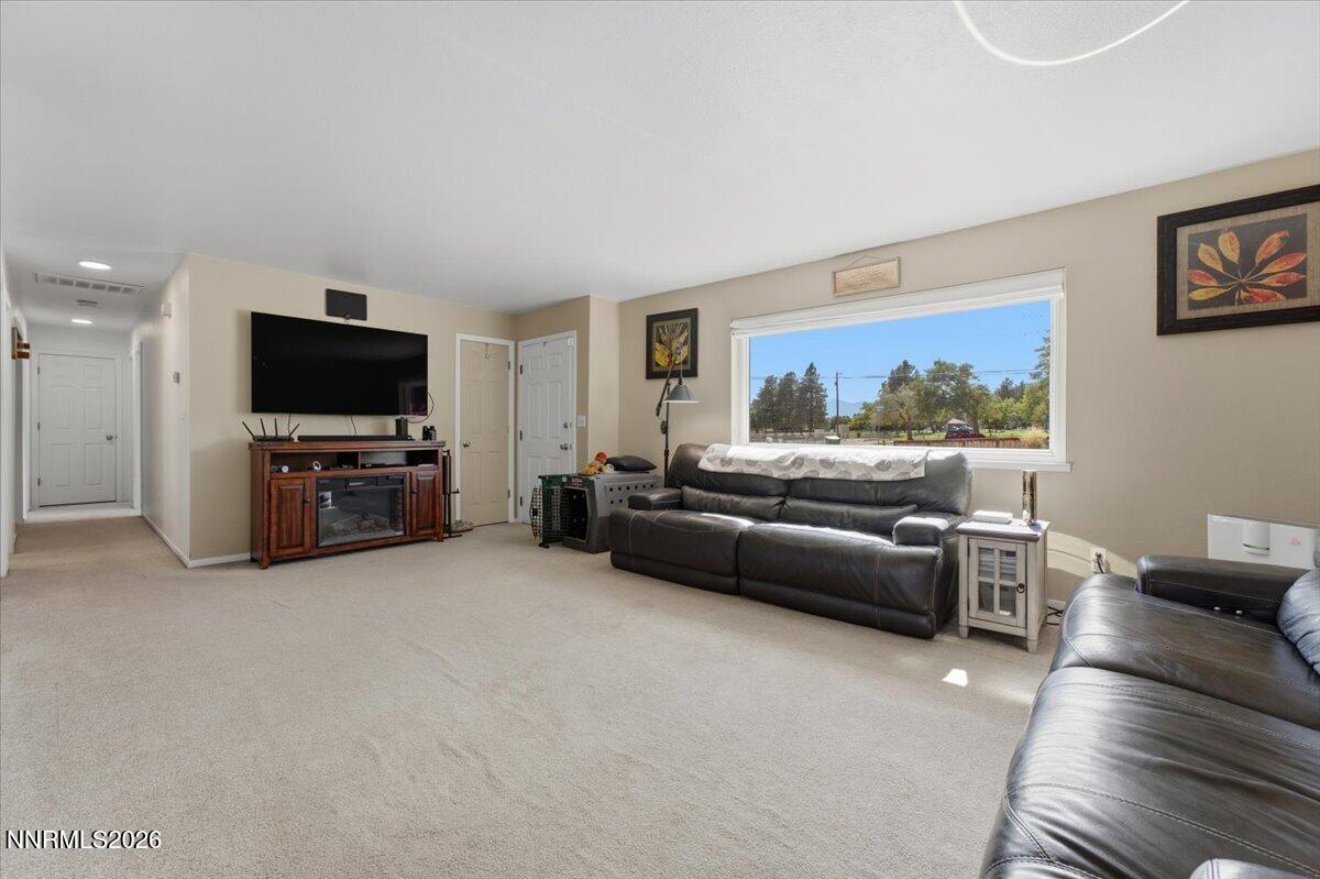 Living room with dark leather sofas, a television, and a wide window overlooking trees.