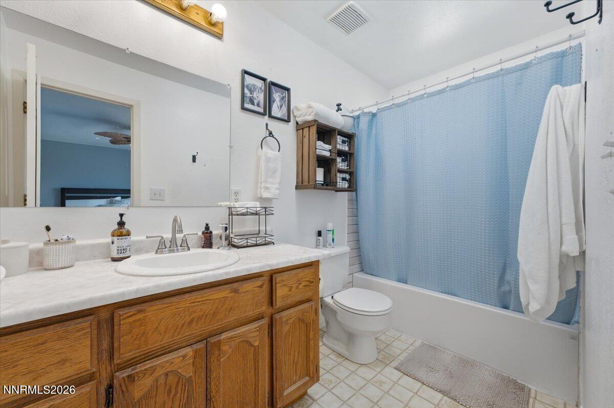 Bathroom with a wood vanity, white countertop, and bathtub behind a light blue shower curtain.