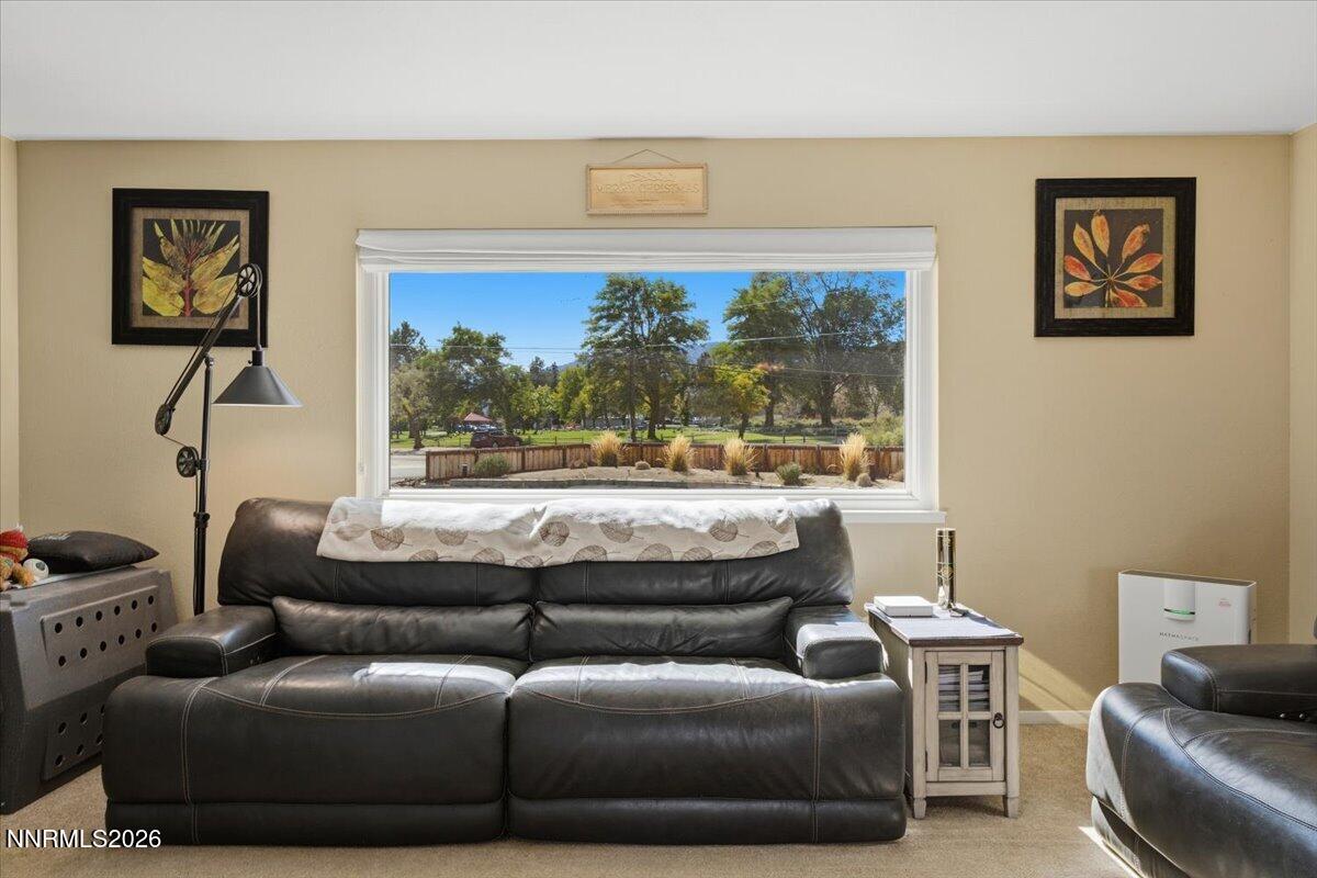 Living room with dark leather sofas and a wide window overlooking a tree-filled park.