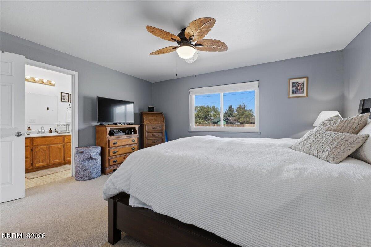 Furnished bedroom with a large bed, wood dressers, and an adjoining bathroom visible through the doorway.