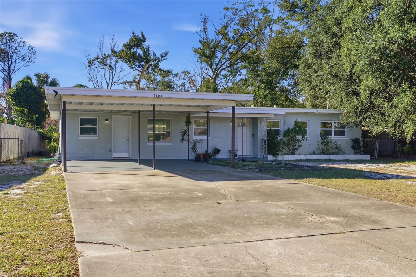 Single-story home with a broad covered carport and concrete driveway.
