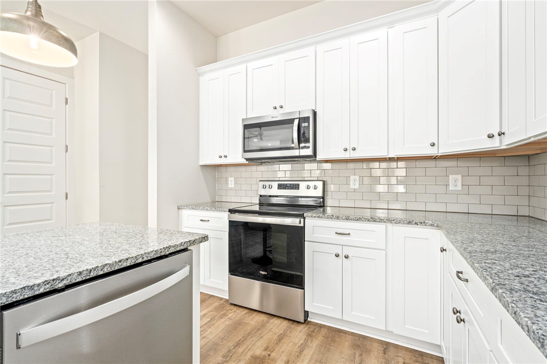 Kitchen with white shaker cabinets, granite counters, subway tile backsplash, and stainless steel appliances.