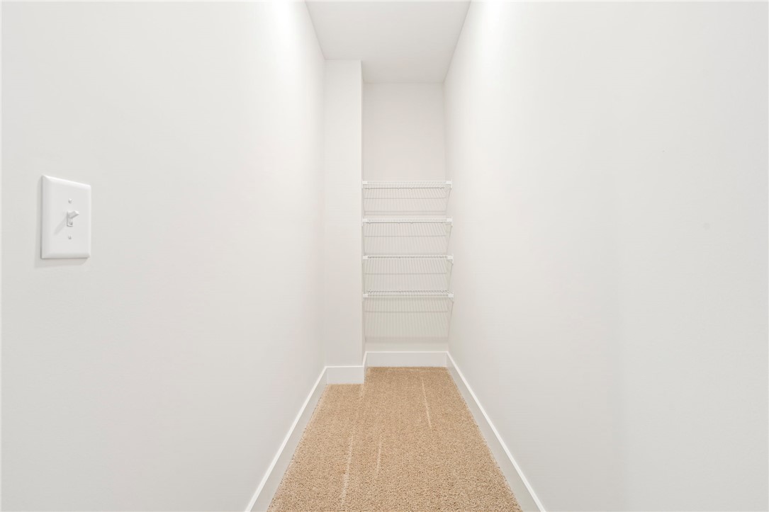 Walk-in storage closet with white wire shelves and beige carpet.