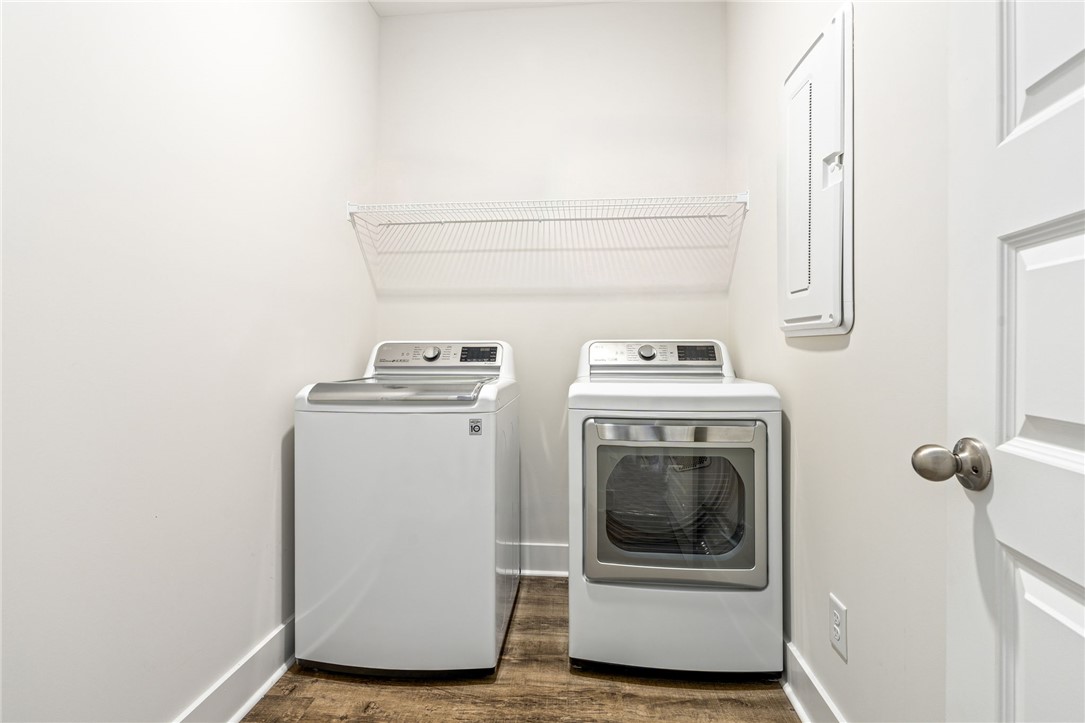 Laundry room with a top-loading washer, front-loading dryer, and overhead wire shelf.