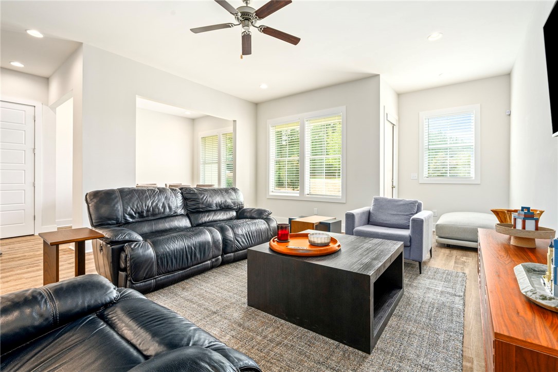 Furnished living room with black leather sofas, a dark coffee table, and a ceiling fan.