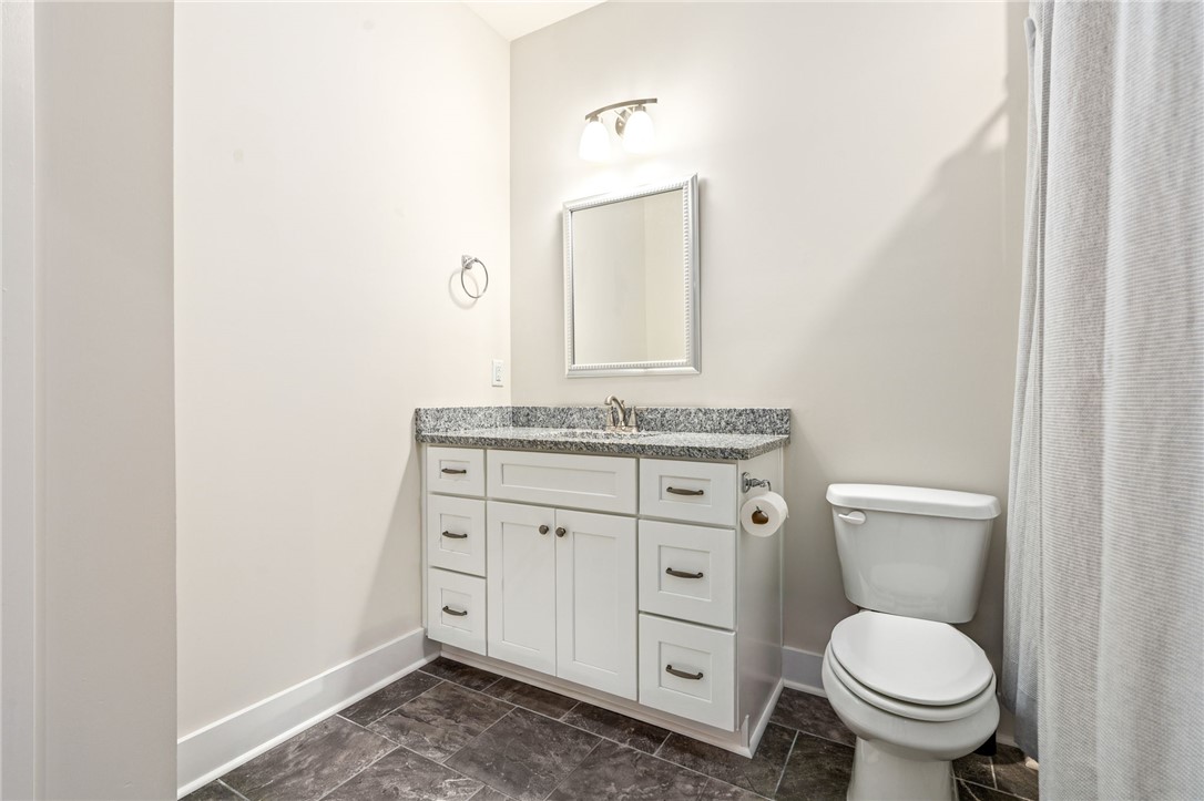 Bathroom with a white vanity, granite countertop, and dark tile floor.