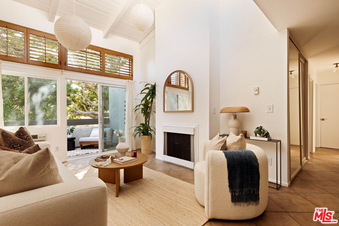 Staged living room with vaulted ceilings, a fireplace, and sliding glass doors opening to a patio.