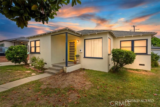 Single-story beige home with a yellow security door and warm-lit windows at sunset.