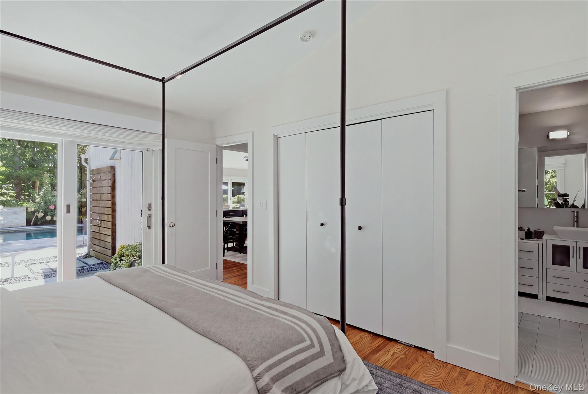 Bedroom with a four-poster bed and sliding glass doors overlooking a backyard pool.