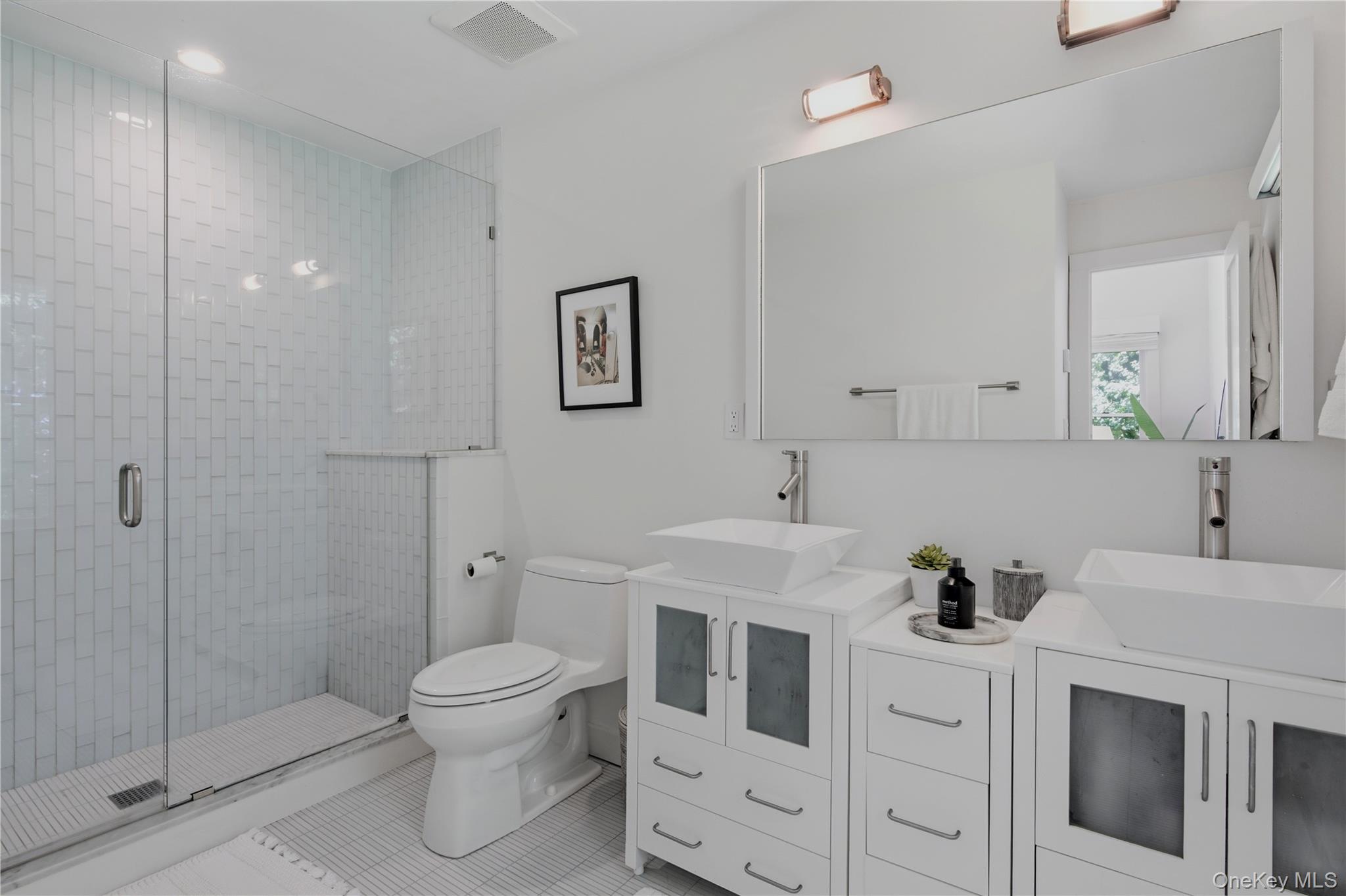 Modern bathroom with a glass-enclosed tile shower and double vessel sinks.