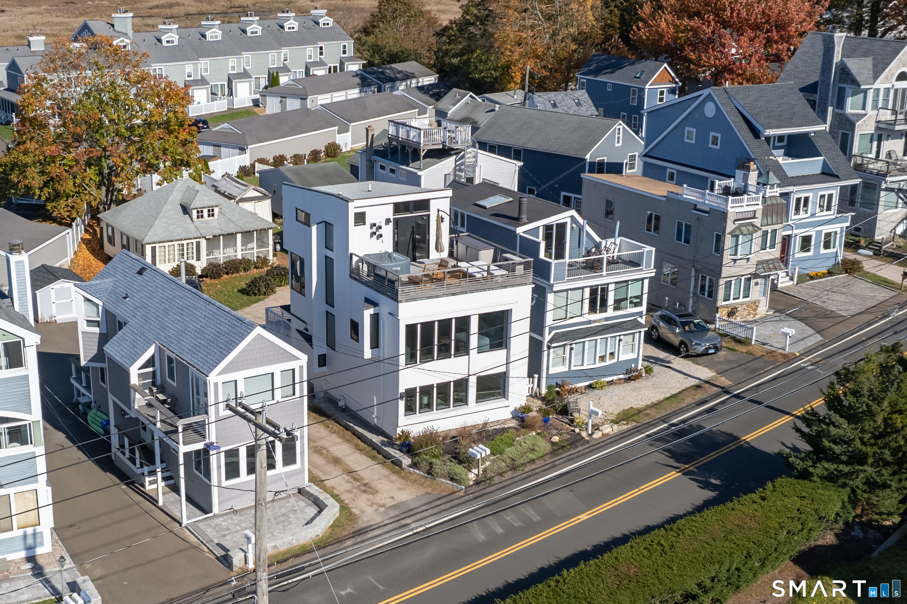 Aerial view of multistory homes with rooftop decks along a residential street.