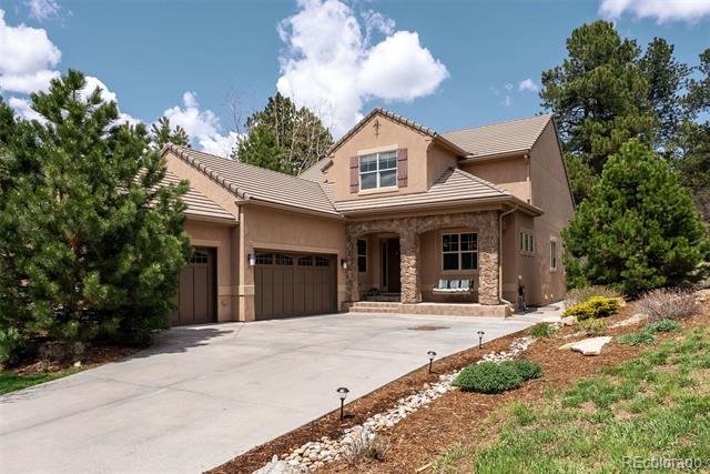 Two-story tan stucco home with a stone entry, attached three-car garage, and broad driveway.