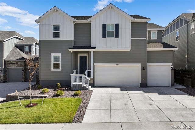 Two-story gray-and-white house with two garage doors and a broad concrete driveway.