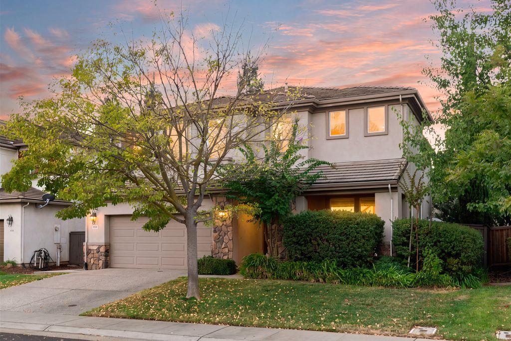 Two-story house with an attached double garage and stone accents beneath a pink dusk sky.