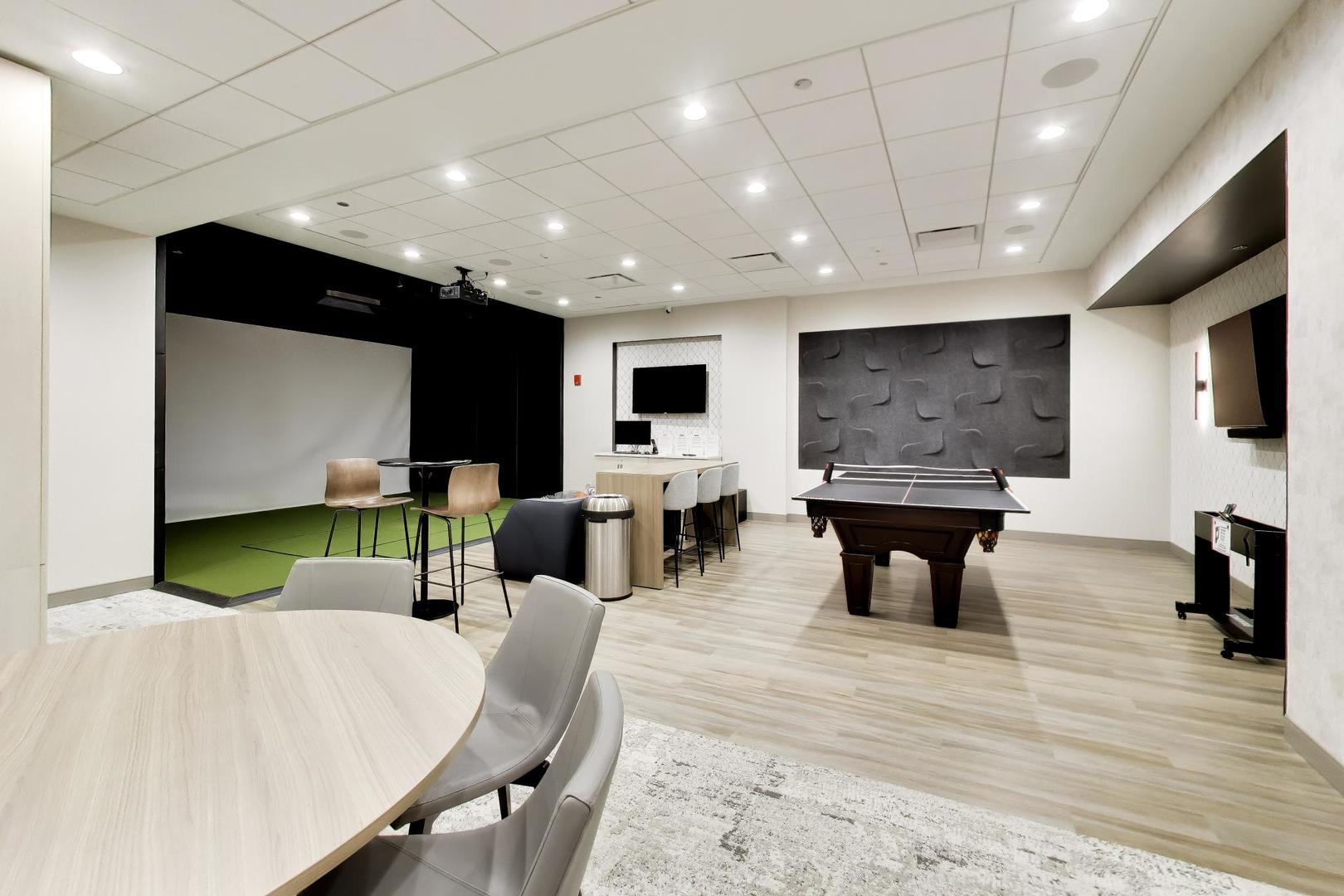 Amenity lounge with a pool table, golf simulator area, and bar seating.