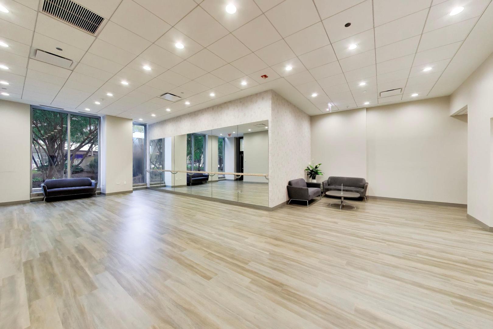 Bright condo exercise room with mirrored wall, ballet barre, and floor-to-ceiling windows.