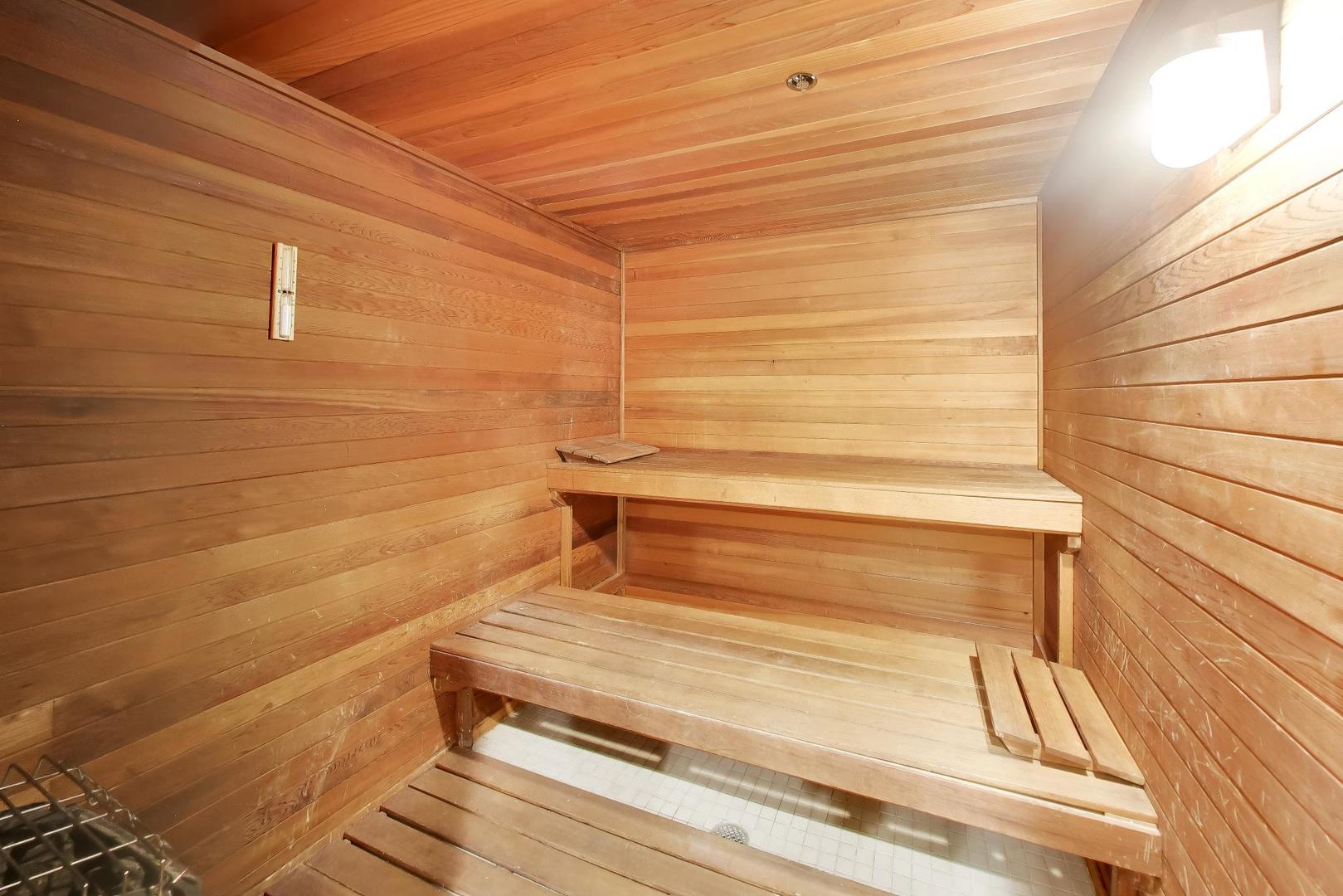 Wood-paneled sauna with tiered wooden benches and a tiled floor.