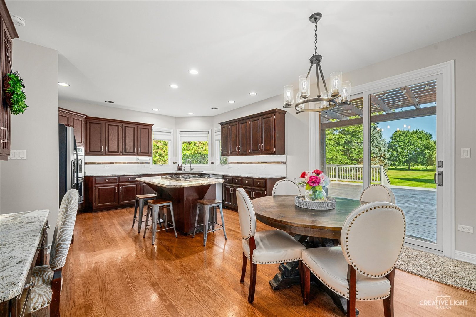 Kitchen and dining area with a cherry island, round table, and sliding doors opening to a deck and lawn.