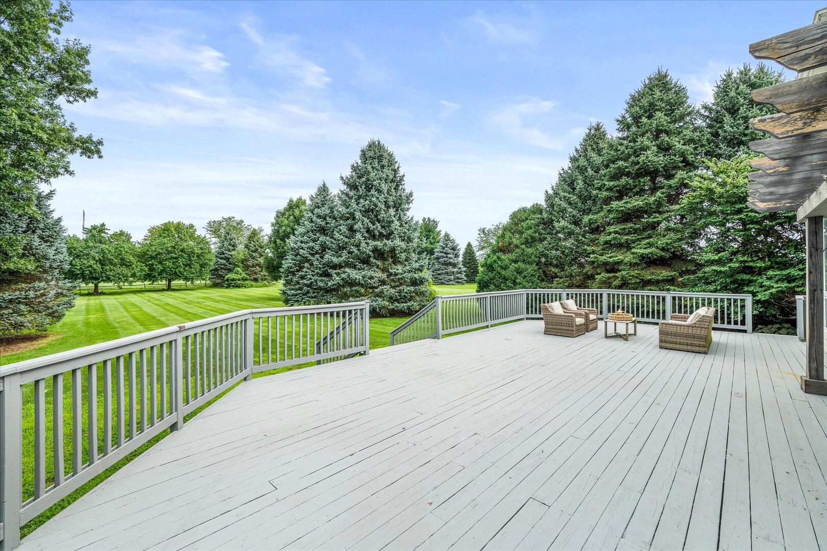 Spacious deck with outdoor seating overlooking a tree-lined lawn.