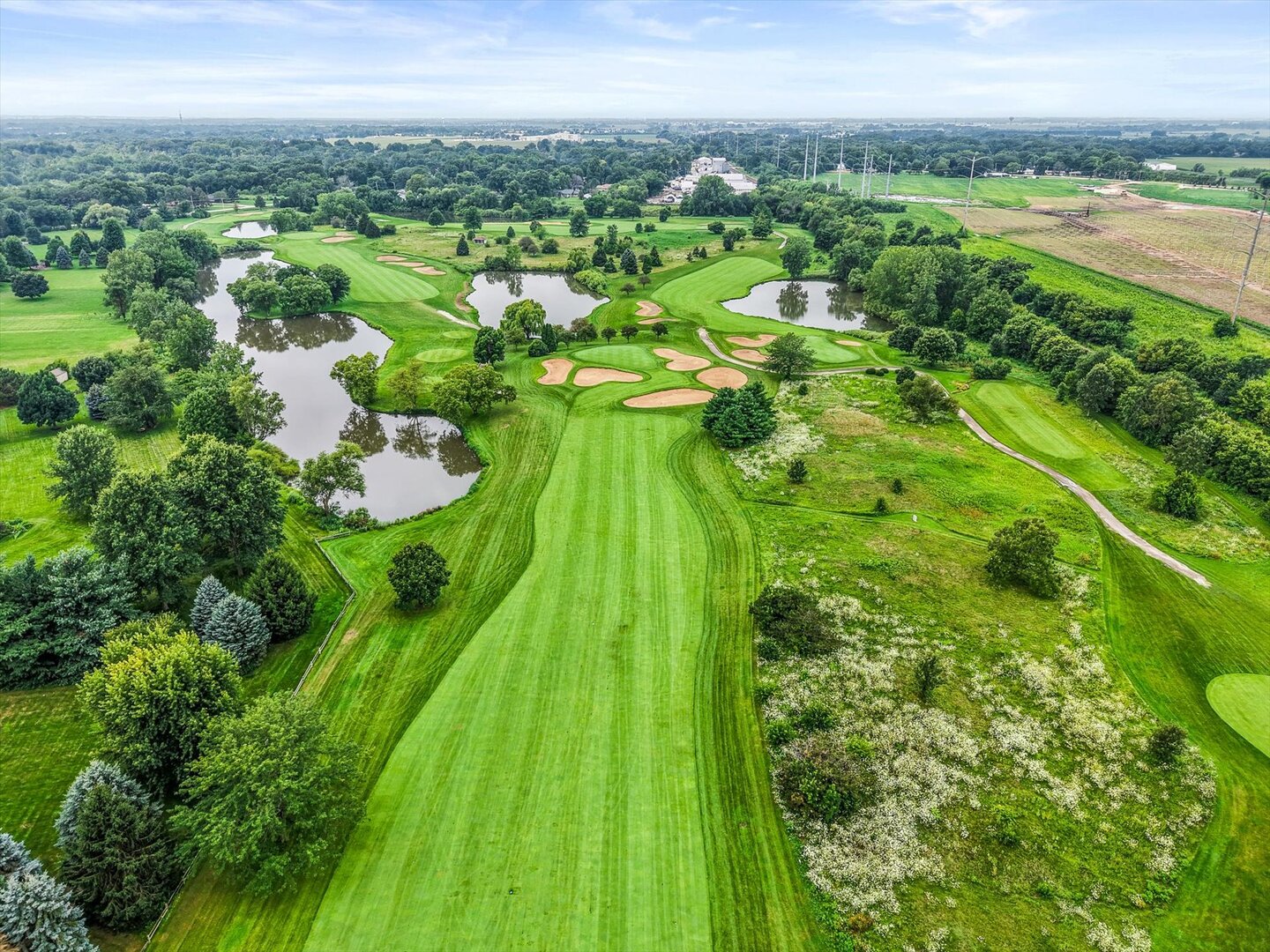 Aerial view of a golf course with winding fairways, sand bunkers, and ponds.