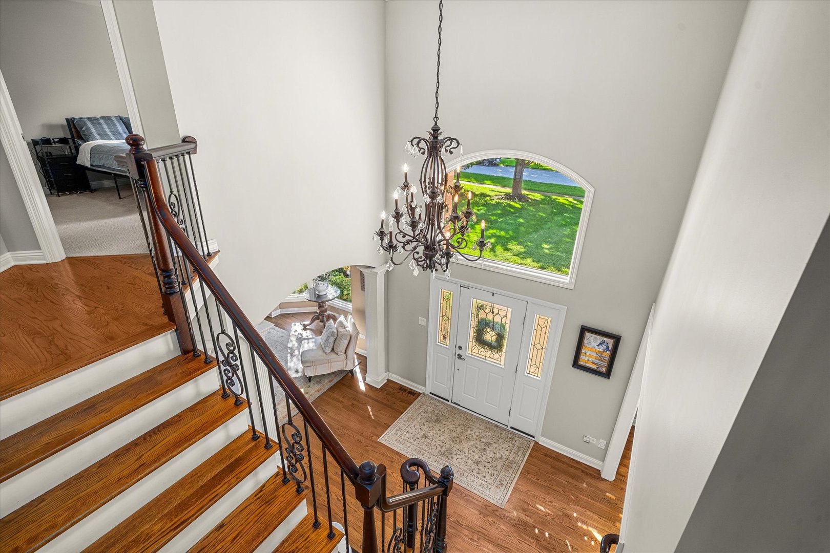Two-story foyer with a curved wood staircase, chandelier, and arched window above the front door.