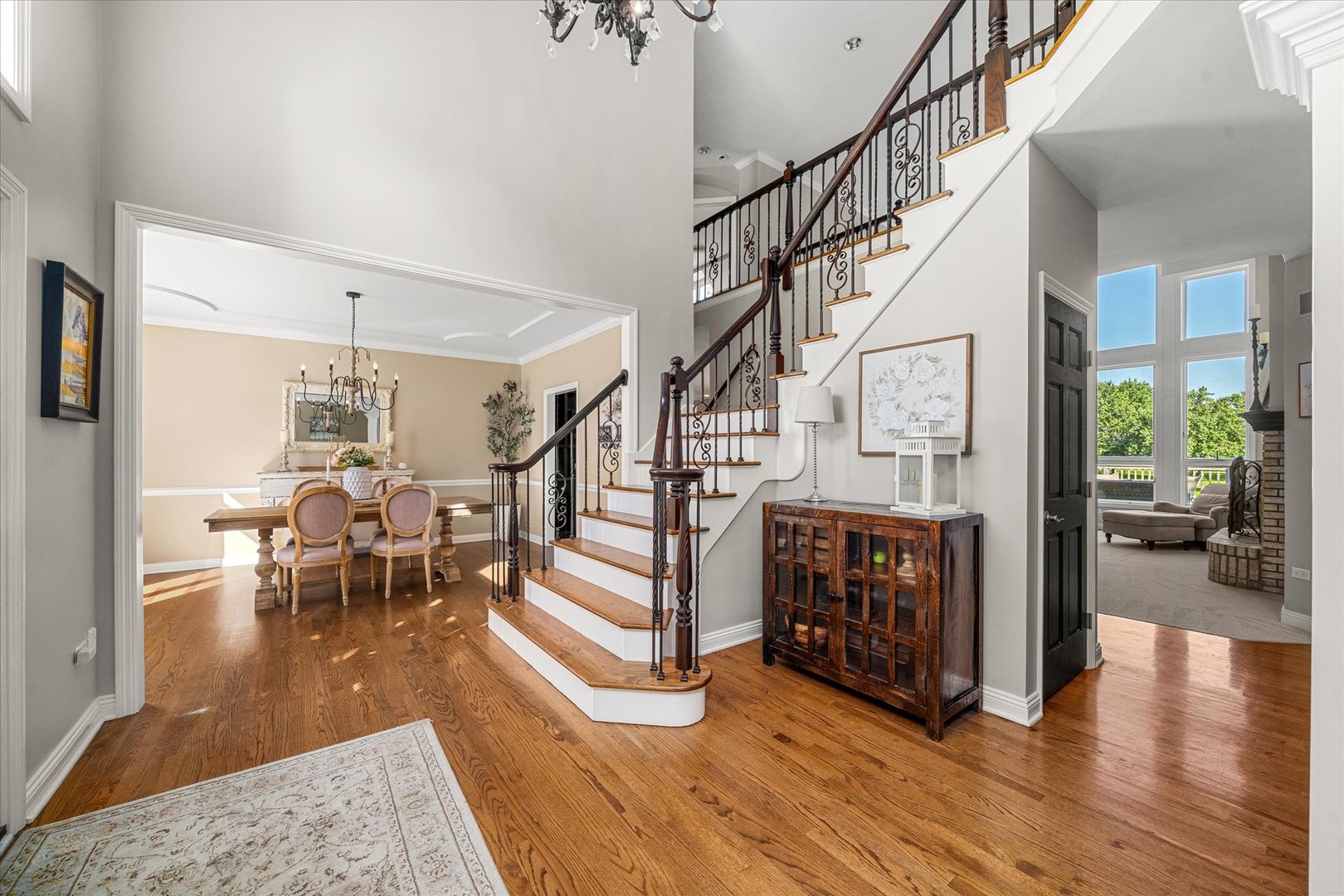 Two-story entry hall with a curved staircase, hardwood floors, and adjoining dining and sitting rooms.