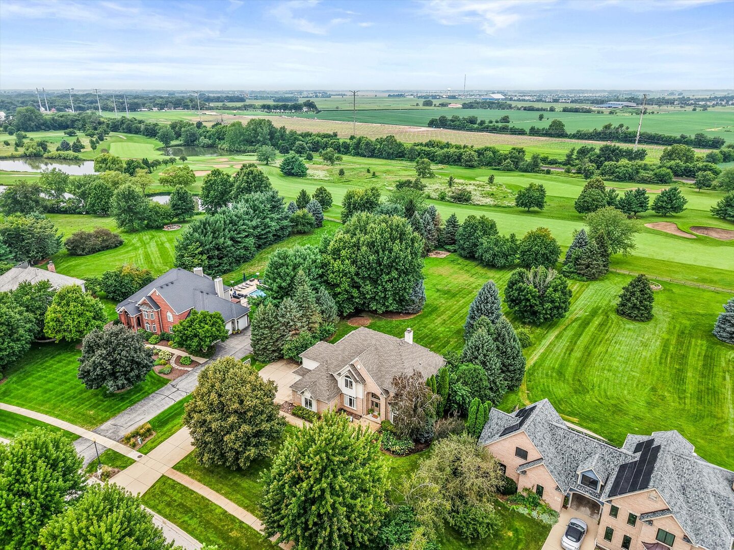 Aerial view of homes beside green golf course fairways and open farmland.