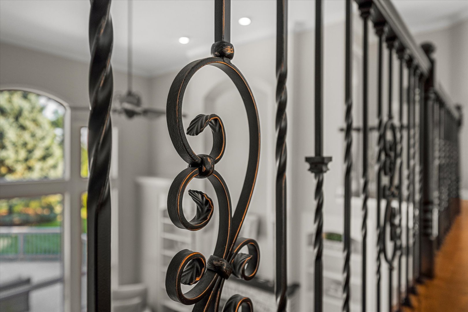 Ornate wrought-iron staircase railing with curled details in a bright interior.