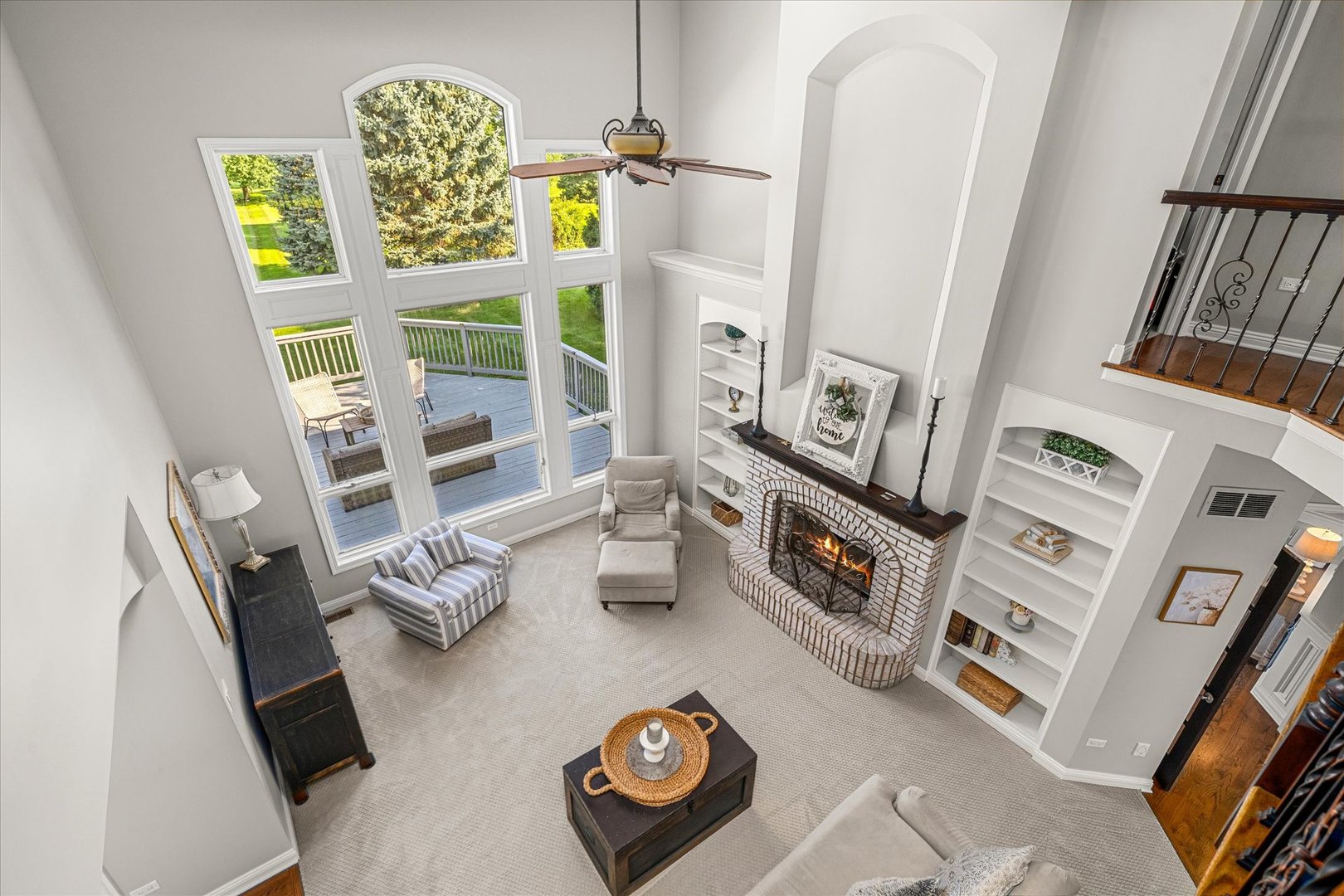 Vaulted living room with tall windows, a brick fireplace, built-in shelves, and neutral seating.